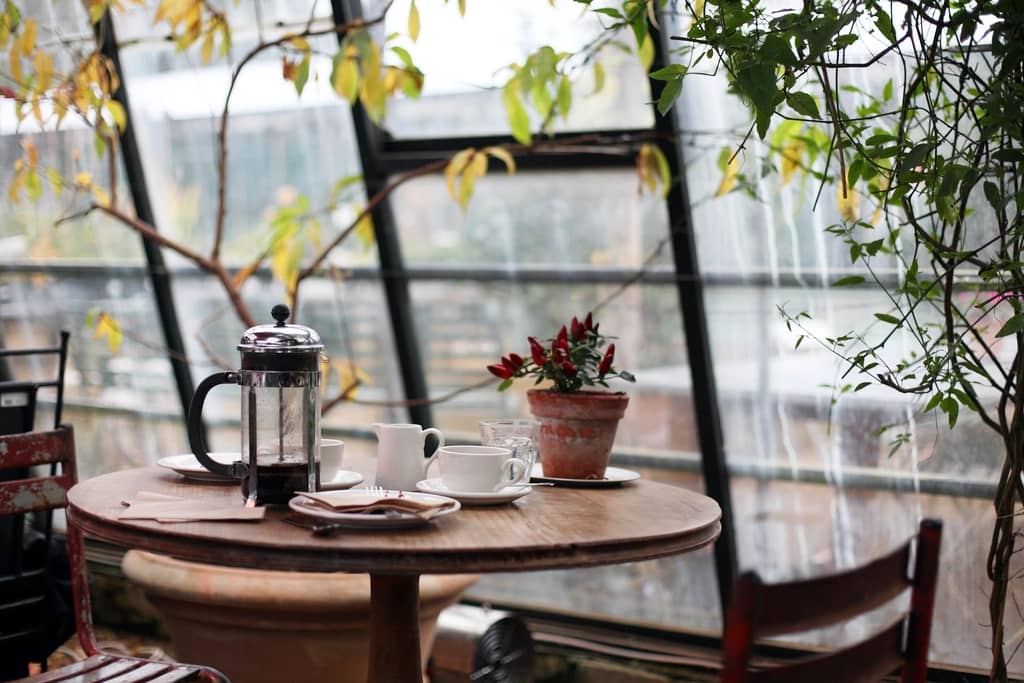 Mesa de café junto à janela, com bule e xícaras